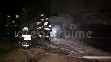 消防队员在夜间扑灭燃烧的汽车